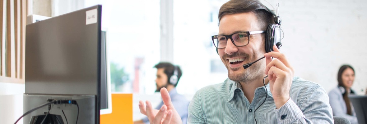 Man looking at a computer while talking on a headpiece 