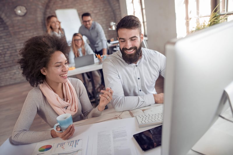 Two marketers at a computer working on their paid media campaign