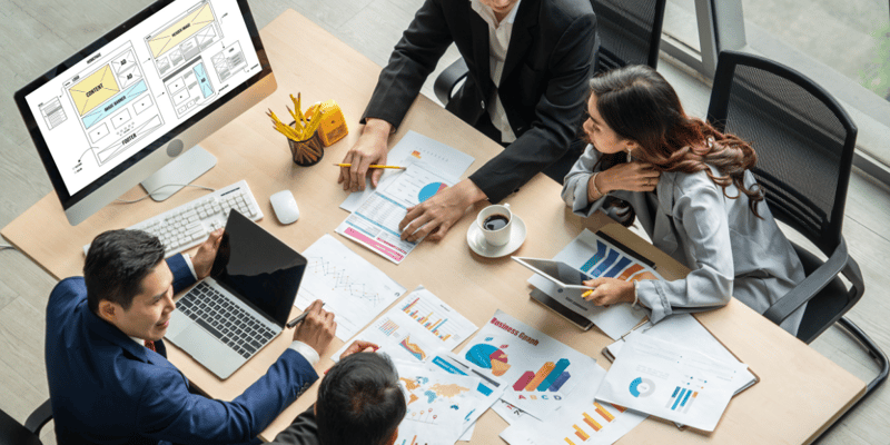 people in an office sitting at a conference table planning marketing activities