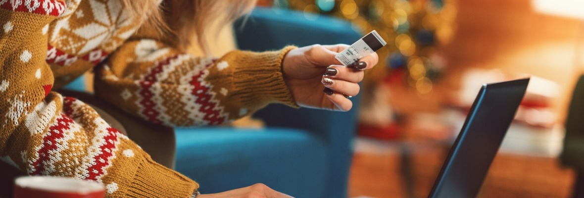 Woman in a Holiday setting looking at a laptop with her credit card at hand 