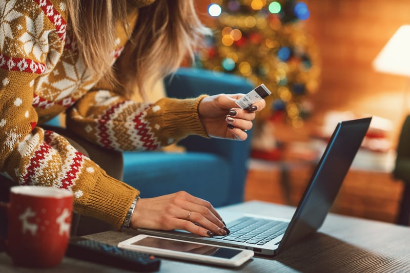 Woman in a Holiday setting looking at a laptop with her credit card at hand 