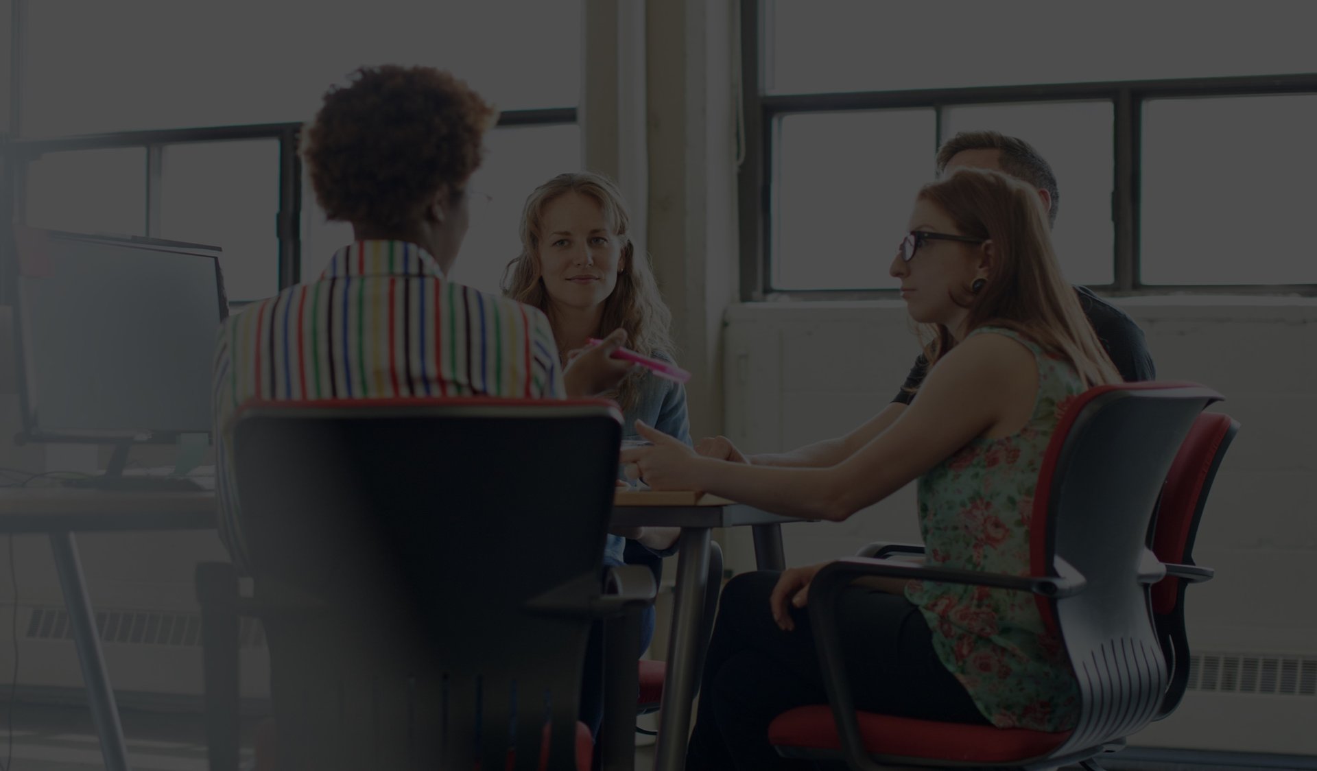 Four employees sitting around a desk