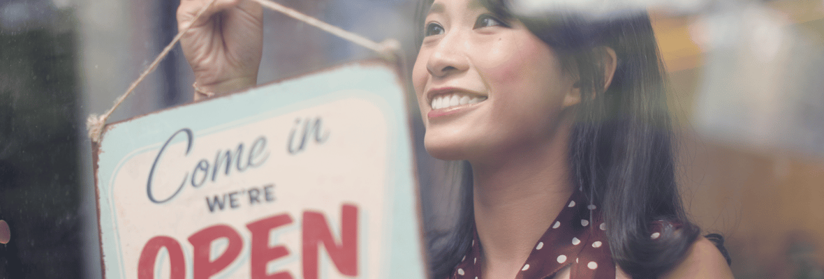 Woman putting up a sign on the front door of her business