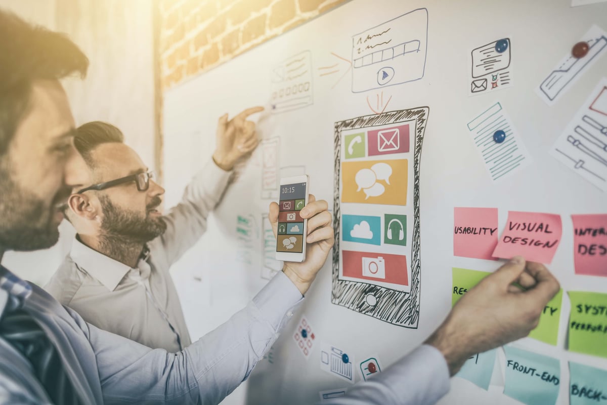 Two men strategizing on a white board