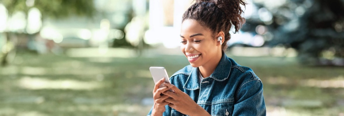 Young woman outdoors reading a message on her phone