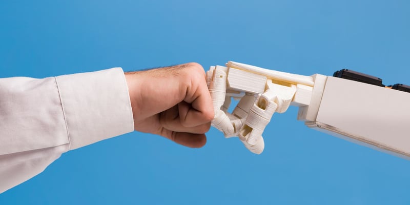 Hand of a man fist bumping the hand of a robot