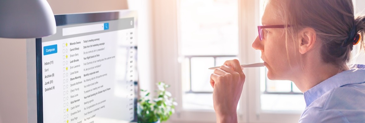 Female business person reading email on computer screen at work