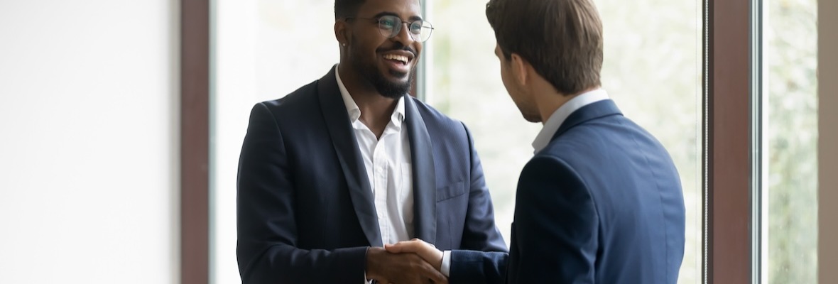 Overjoyed multiethnic businessmen shake hands greeting getting acquainted in office