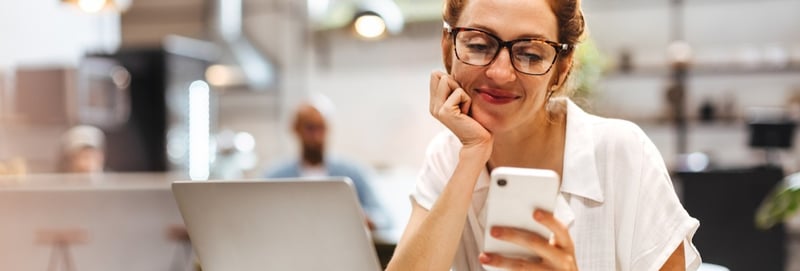 Caucasian woman taking a break from work to browse her phone in a cafe