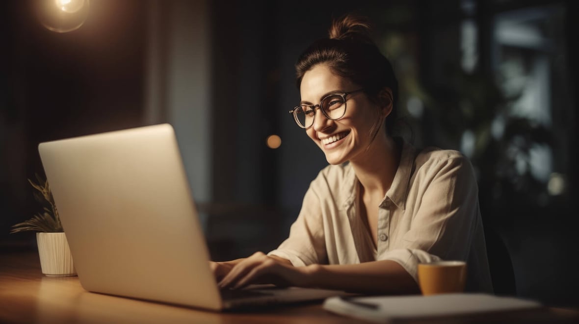 A smiling woman is working on a laptop
