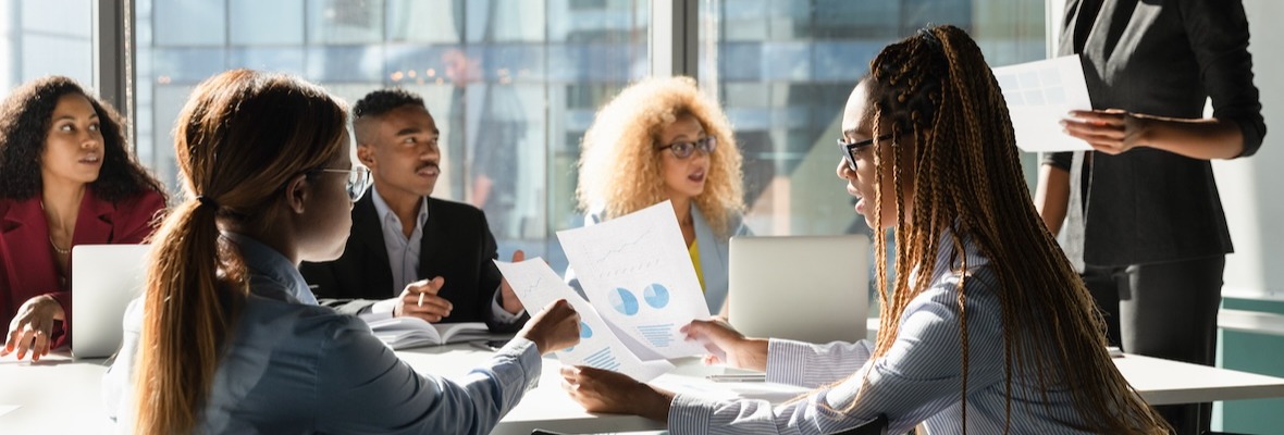 Multiethnic staff group discuss sales result on briefing using paper reports with charts