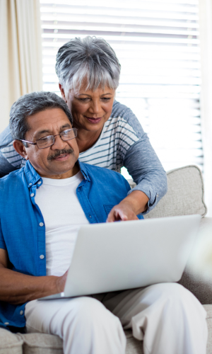 Two senior citizens in a couch looking at a computer