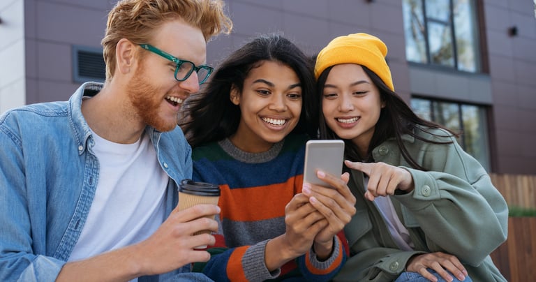 Three prospective higher education students engaging with social media marketing on a mobile device.