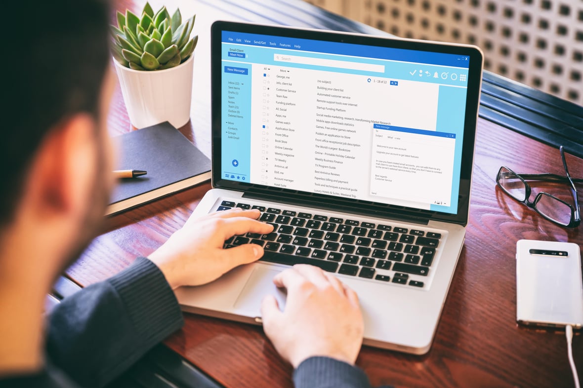 Close up image of two hands typing in a laptop while checking emails