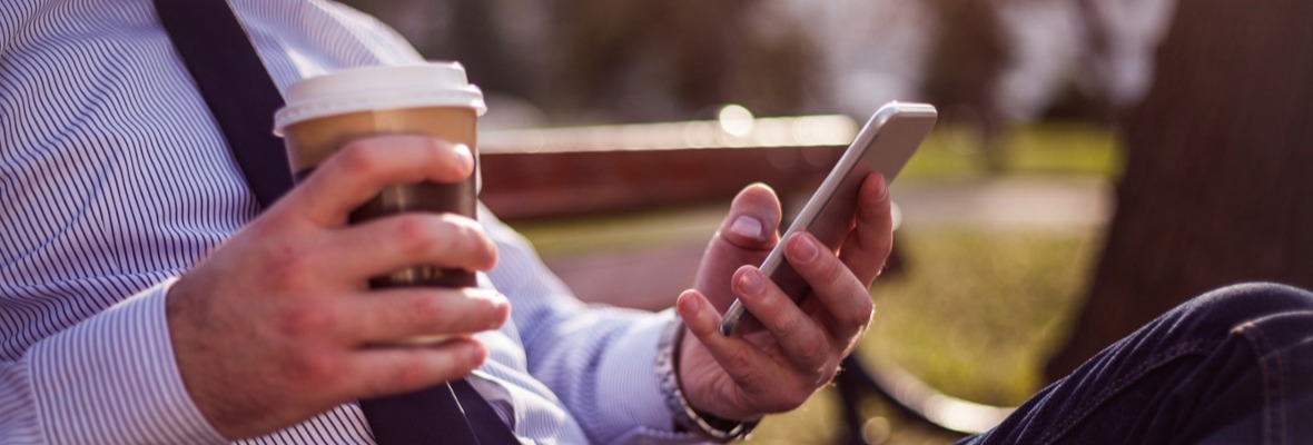 Man holding a coffee on one hand and his cellphone on the other hand