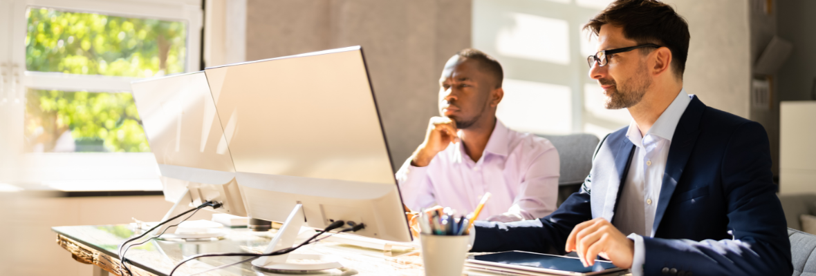 Two salesmen review HubSpot attribution reports on computers. 