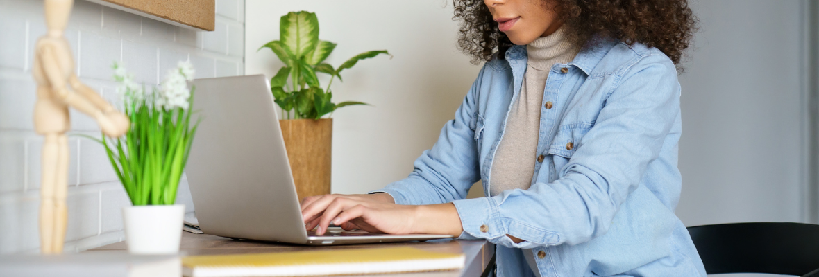 A middle aged woman writes a draft of a blog on a laptop. 