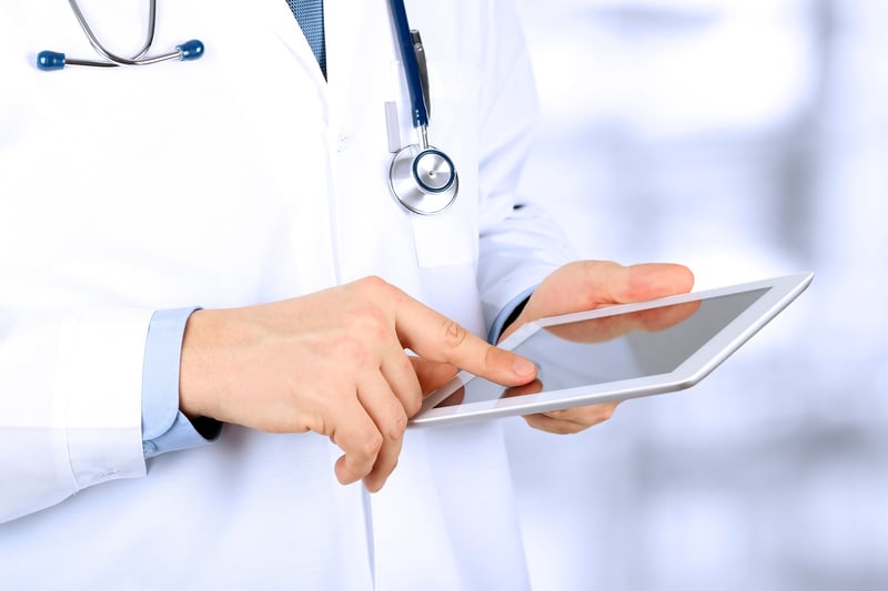 A doctor looking at information on a tablet. 