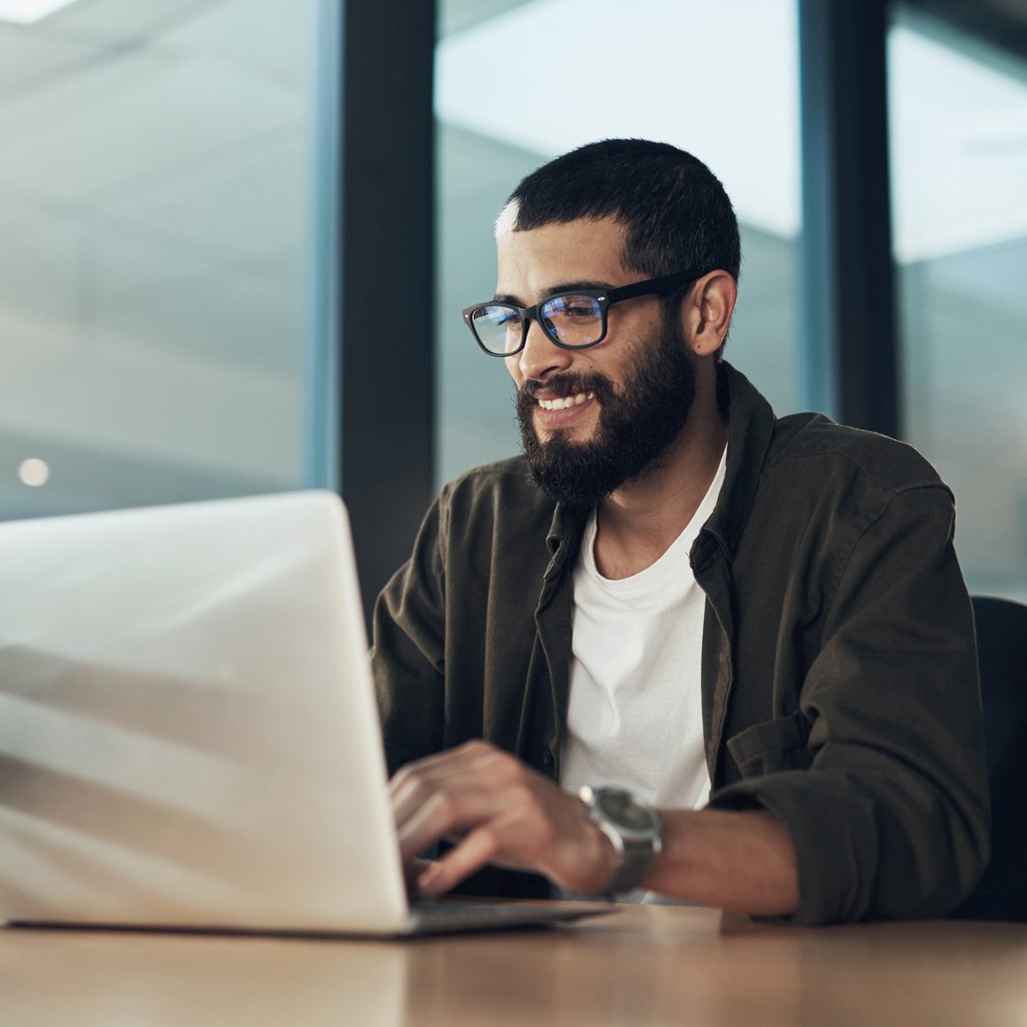 Marketer working on his laptop while smiling