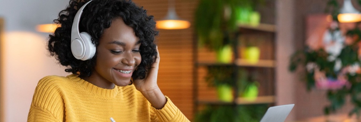 Woman smiling while wearing headsets and working on computer