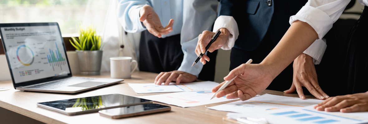 Close up image of several hands working on a table on marketing processes 