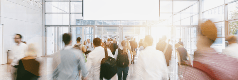A group of people walking to the entrance of a trade show