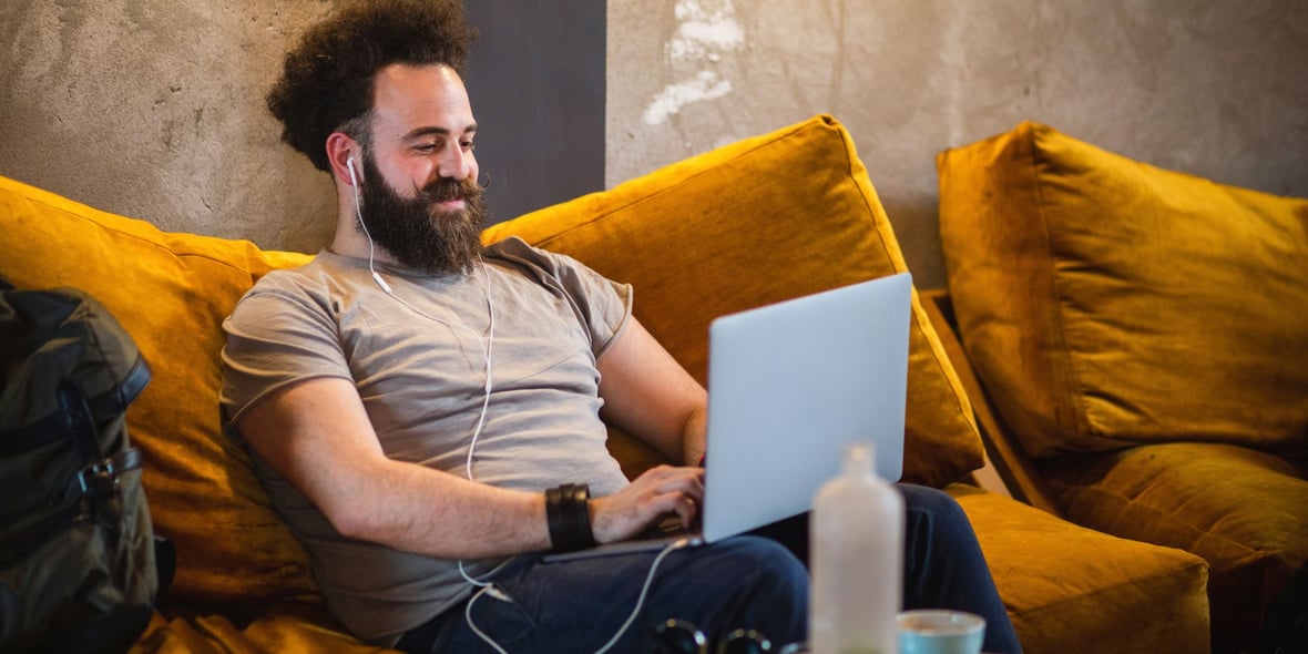 Man sitting in a couch while writing a blog on his laptop