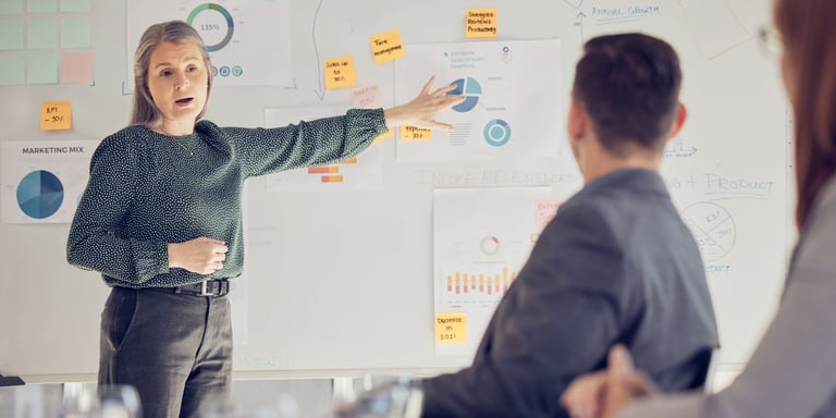 Marketer at a whiteboard explaining their sales strategy to the team