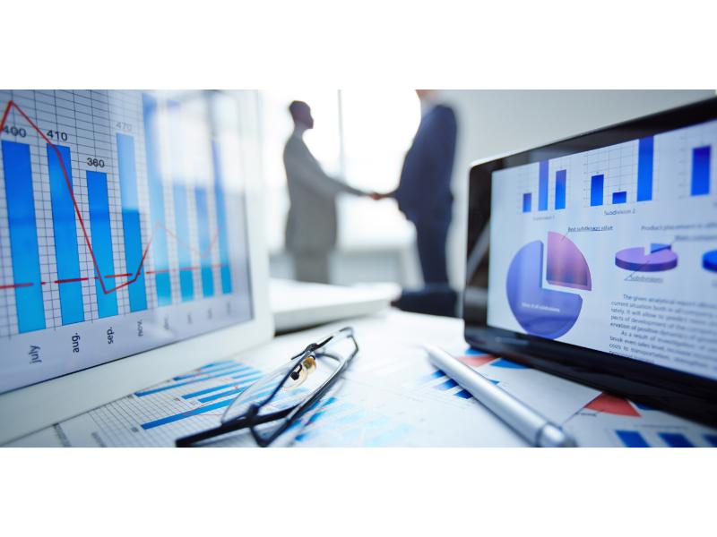 Two man shaking hands in the background and closeup image of computers with metrics up front