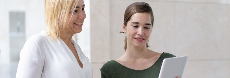 Two women looking at a tablet while smiling