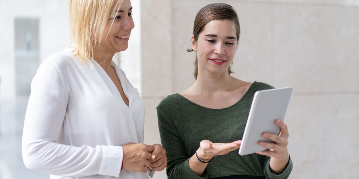 Two women looking at a tablet while smiling