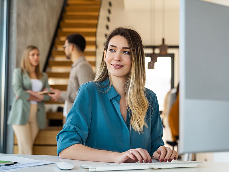 Young business woman looking at computer monitor during working day in office