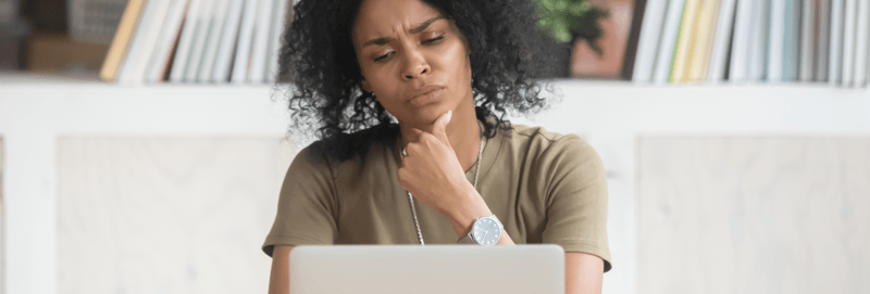 woman looking at a laptop looking confused