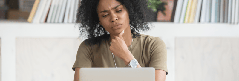 woman looking at a laptop looking confused