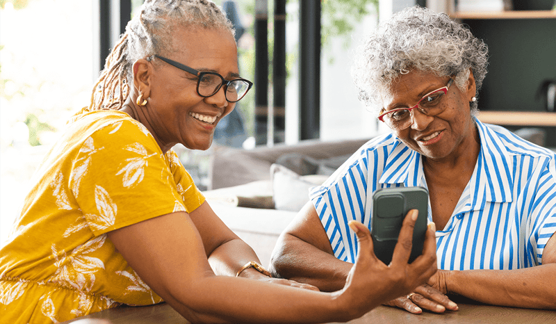 two seniors collaborating to use a mobile device