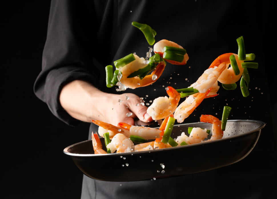 chef cuisinant des crevettes et des légumes