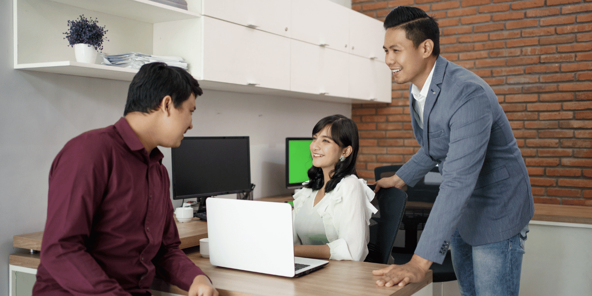 Three coworkers talking at a desk