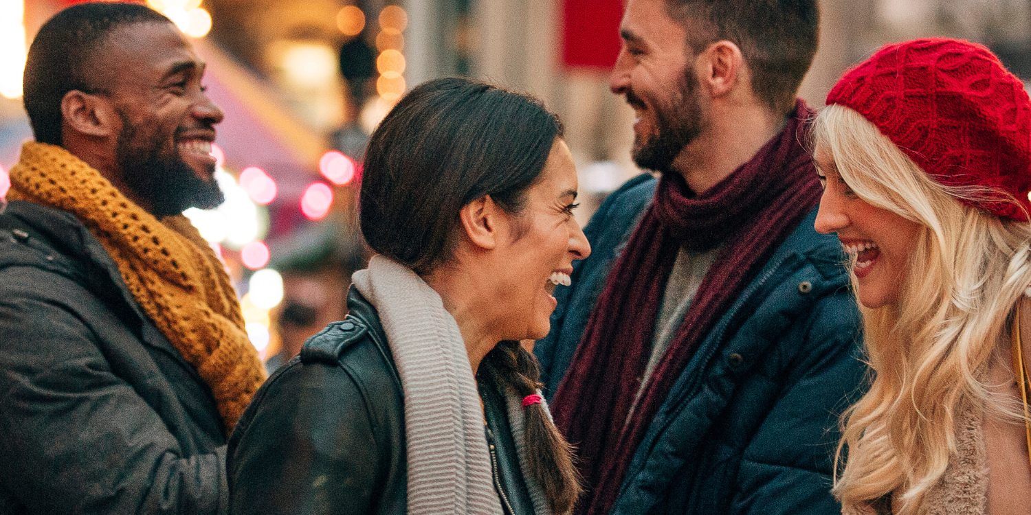 A group of friends laughing with Holiday lights in the background